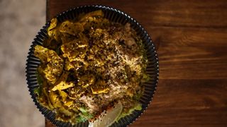 Overhead shot of a bowl of seitan curry with rice and wedge of lime sitting atop a bench