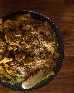 Overhead shot of a bowl of seitan curry with rice and wedge of lime sitting atop a bench