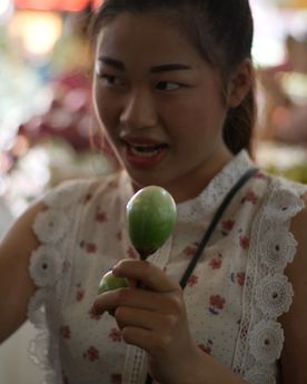 Girl explaining about a round Asian vegetable found at a wet market in Thailand