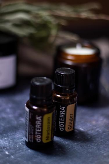 Two bottles of essential oils standing in front of a candle 