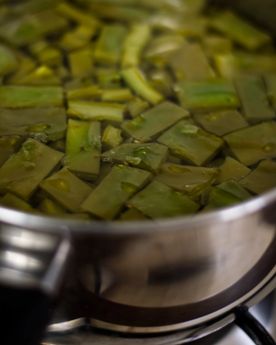 Sliced cactus pads being boiled in a pot over the stove