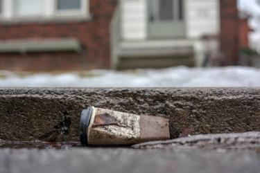 A dirty disposable coffee cup left on the street