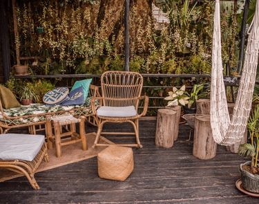 Outdoor are of restaurant The Nesting Table at glamping boutique hotel The Birdhouse El Nido showing a hammock, wooden tables and chairs surrounded by lush plants