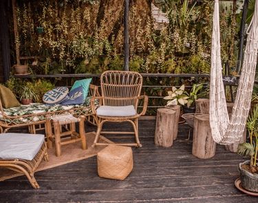 Outdoor are of restaurant The Nesting Table at glamping boutique hotel The Birdhouse El Nido showing a hammock, wooden tables and chairs surrounded by lush plants 