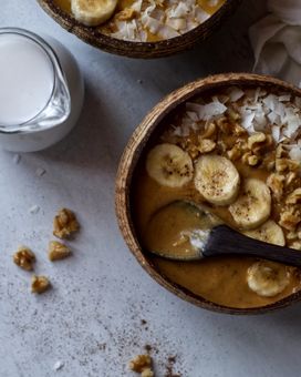 Top down view of smoothie bowls and a jug of coconut milk