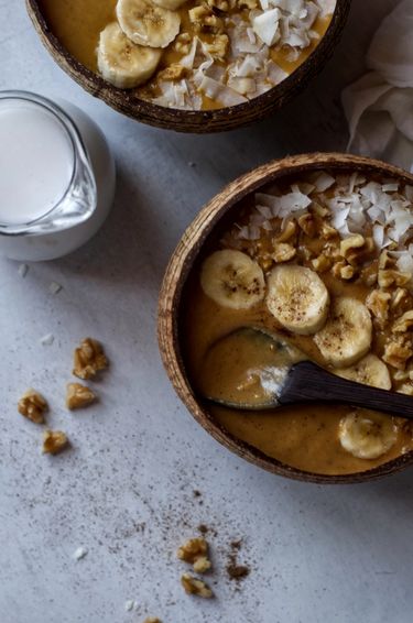 Top down view of smoothie bowls and a jug of coconut milk 