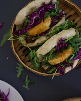 Bao buns (gua bao) with rocket, cabbage, and fried goats cheese in a bamboo steamer