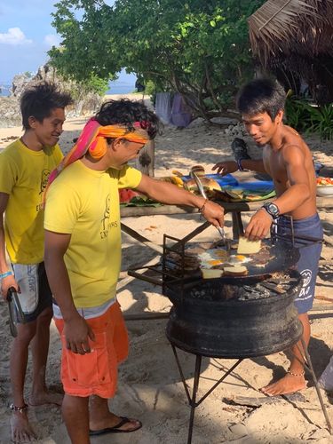 Men cooking food on a bbq on the beach