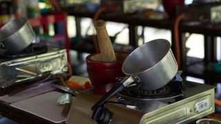 An outdoor cooking school with pots and portable stoves lined up