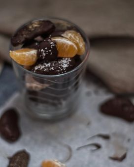 Chocolate coated clementine segments stacked in a glass