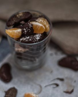Chocolate coated clementine segments stacked in a glass 