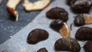 Scattered clementines coated in chocolate, surrounded by whole clementines