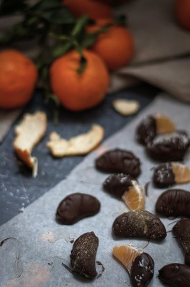 Scattered clementines coated in chocolate, surrounded by whole clementines