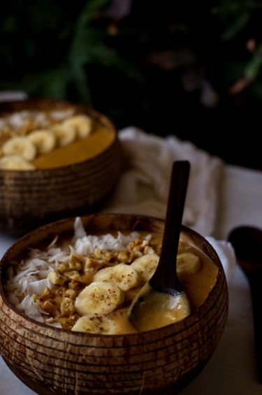 Close up shot of two smoothies in coconut bowls besides and indoor plant