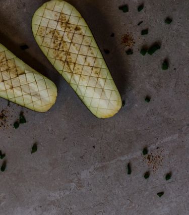 Two halves of a raw aubergine scored in a criss-cross fashion