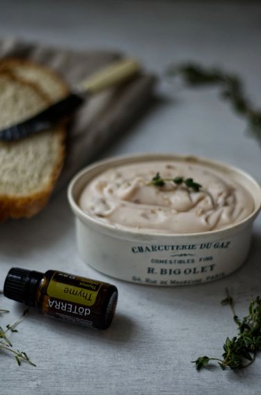 Butter in a ceramic dish with a bottle of Thyme essential oil lying flat next to the dish