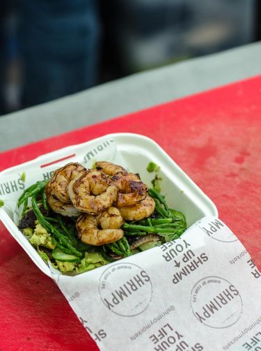 Picture of burger with samphire and grilled prawns from Shrimpy, a London based food stall specialising in shrimp burgers, preparing a shrimp burger at their food stall in Broadway Market