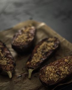 Close up of 4 halves of a aubergine on baking parchment on a baking tray 