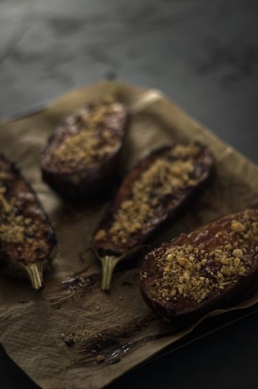 Close up of 4 halves of a aubergine on baking parchment on a baking tray