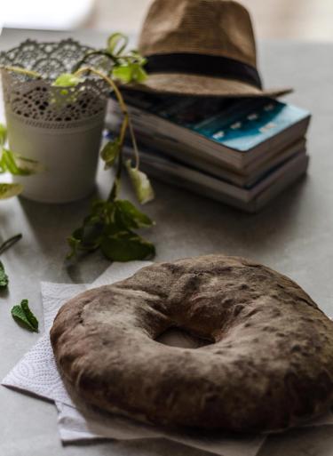 Picture of a Maltese bread also known as Maltese ftira, surrounded by a pot, books and a hat