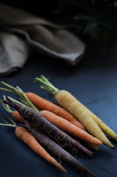 Colourful baby carrots stacked on top of each other on a surface