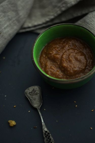 Green bowl filled with miso glaze surrounded by a spoon and a linen cloth.