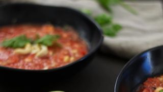 Shot of two bowls filled with watermelon gazpacho surrounded by two halves of lime