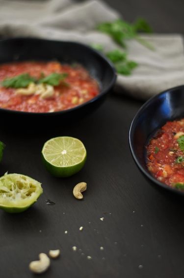 Shot of two bowls filled with watermelon gazpacho surrounded by two halves of lime