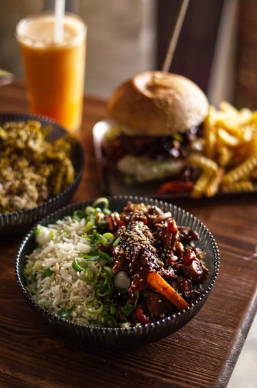 60 degree angle shot of two bowls food, a burger and a glass of juice