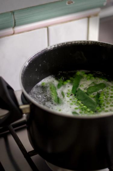 A pot of boiling water with English peas and Romano Beans 