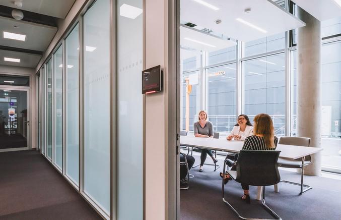 People sitting in conference room with Eyrise privacy glazing