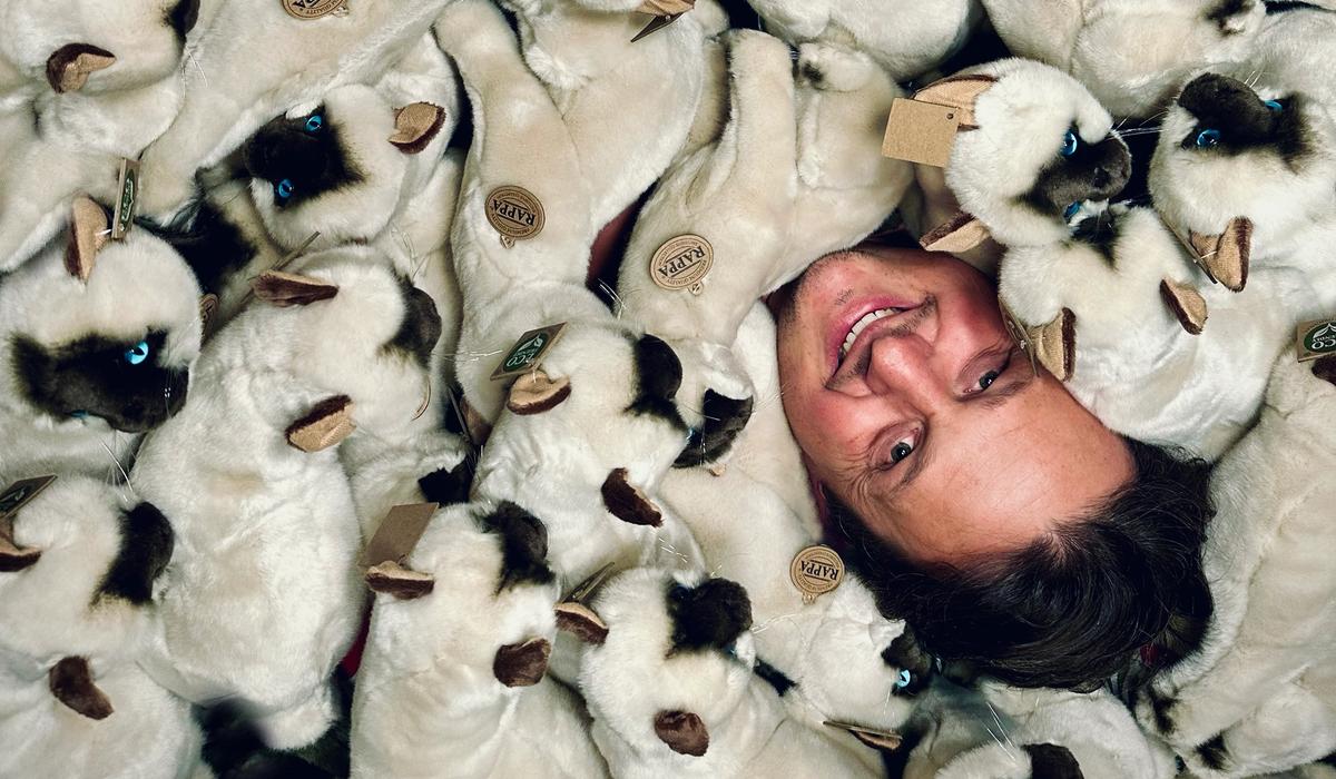 Oliver Ruhm in einem Riesenhaufen Katzen.