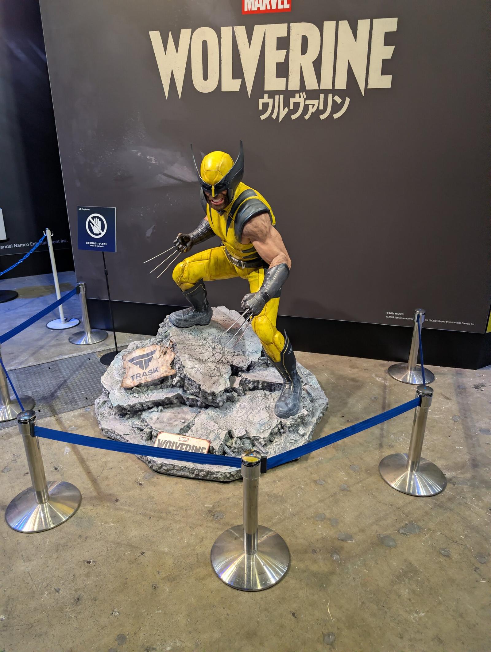 En staty av Wolverine i gul dräkt på en klippformation, avspärrad med blå band.