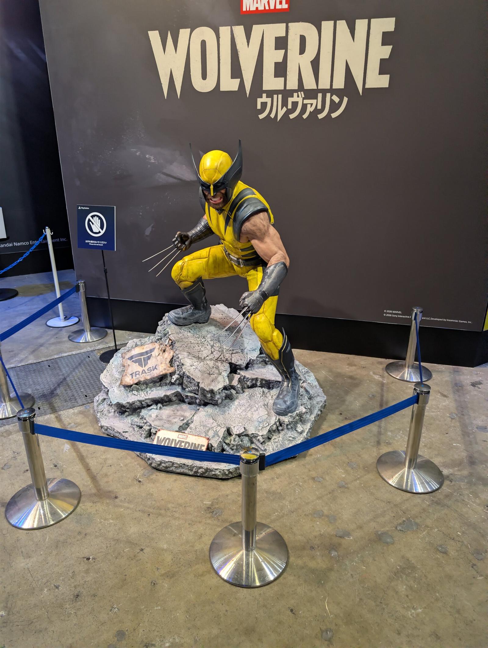En staty av Wolverine i gul dräkt på en klippformation, avspärrad med blå band.