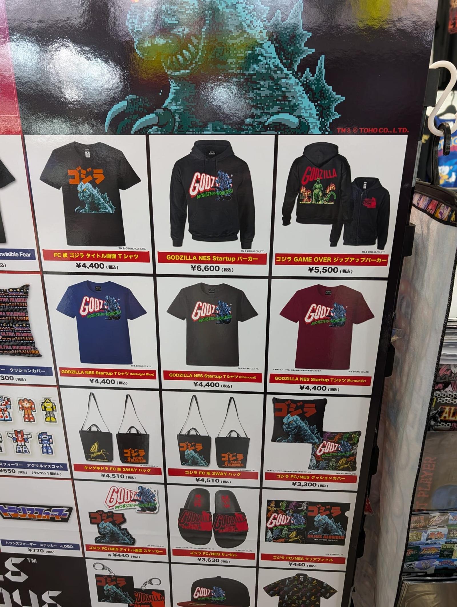 Prislista med Godzilla-tröjor, väskor och tofflor i en merchandisebutik.