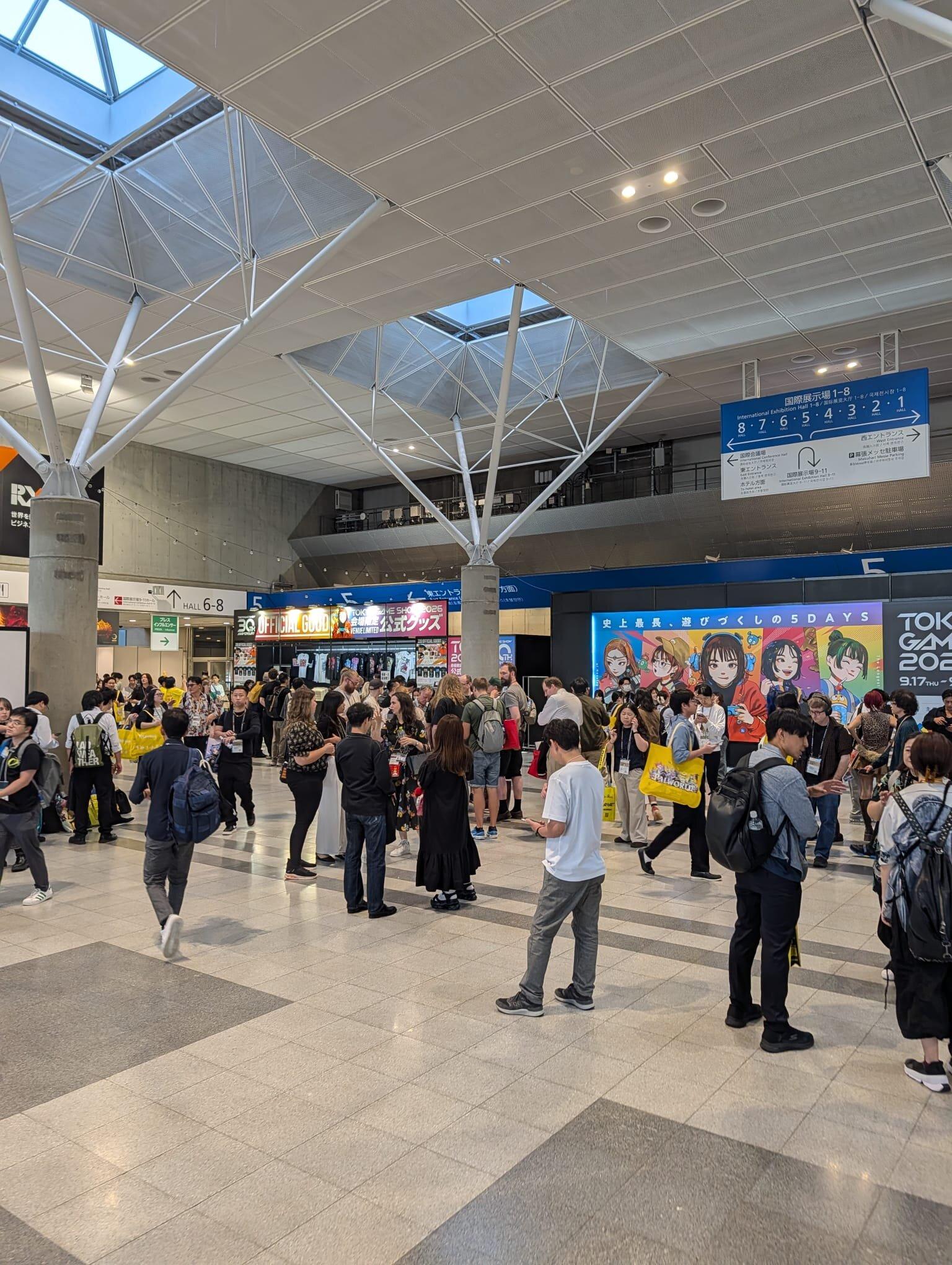 Entréhallen på Makuhari Messe fylld med besökare, med banderoller för Tokyo Game Show 2026 i bakgrunden.