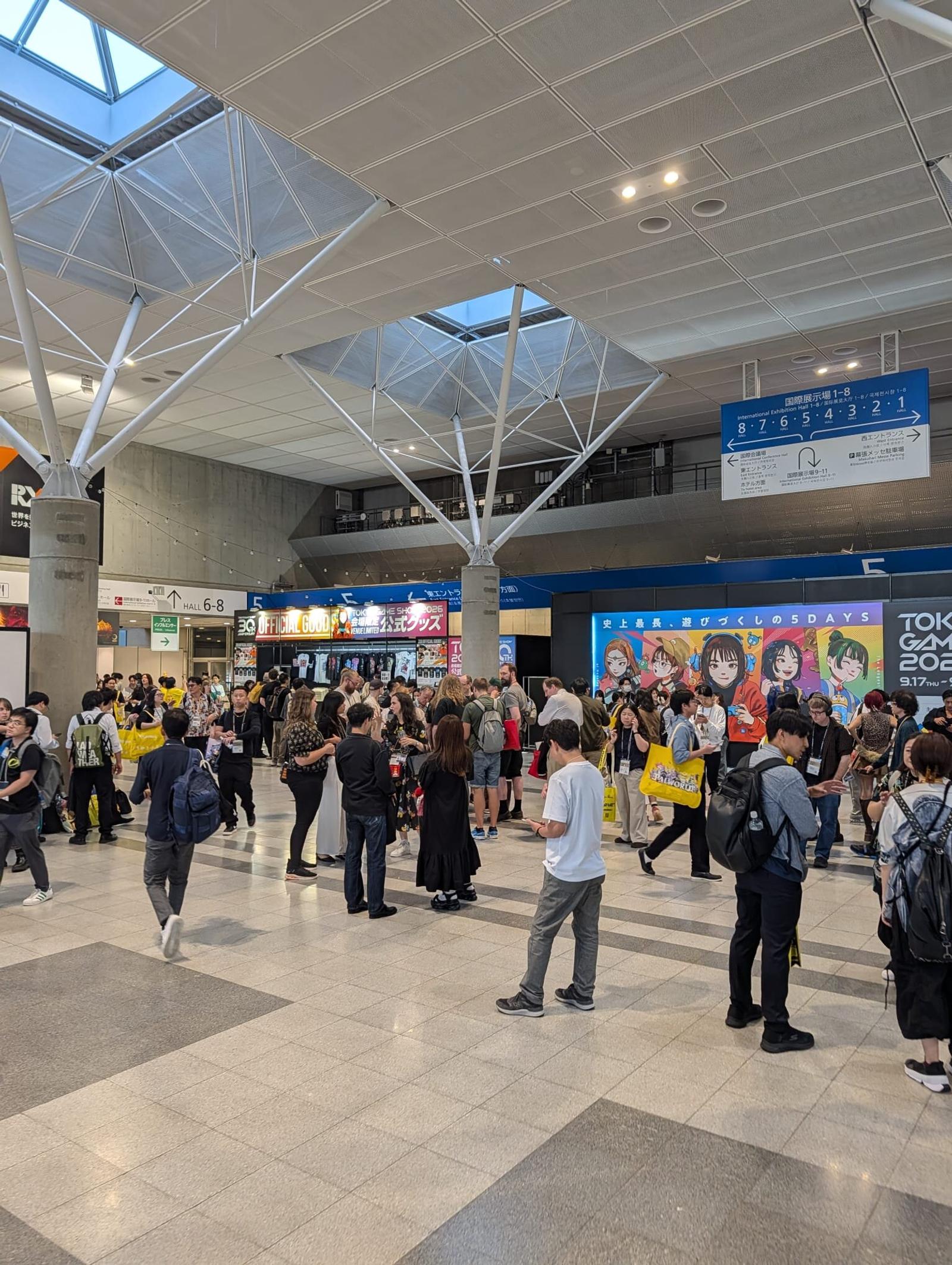 Entréhallen på Makuhari Messe fylld med besökare, med banderoller för Tokyo Game Show 2026 i bakgrunden.