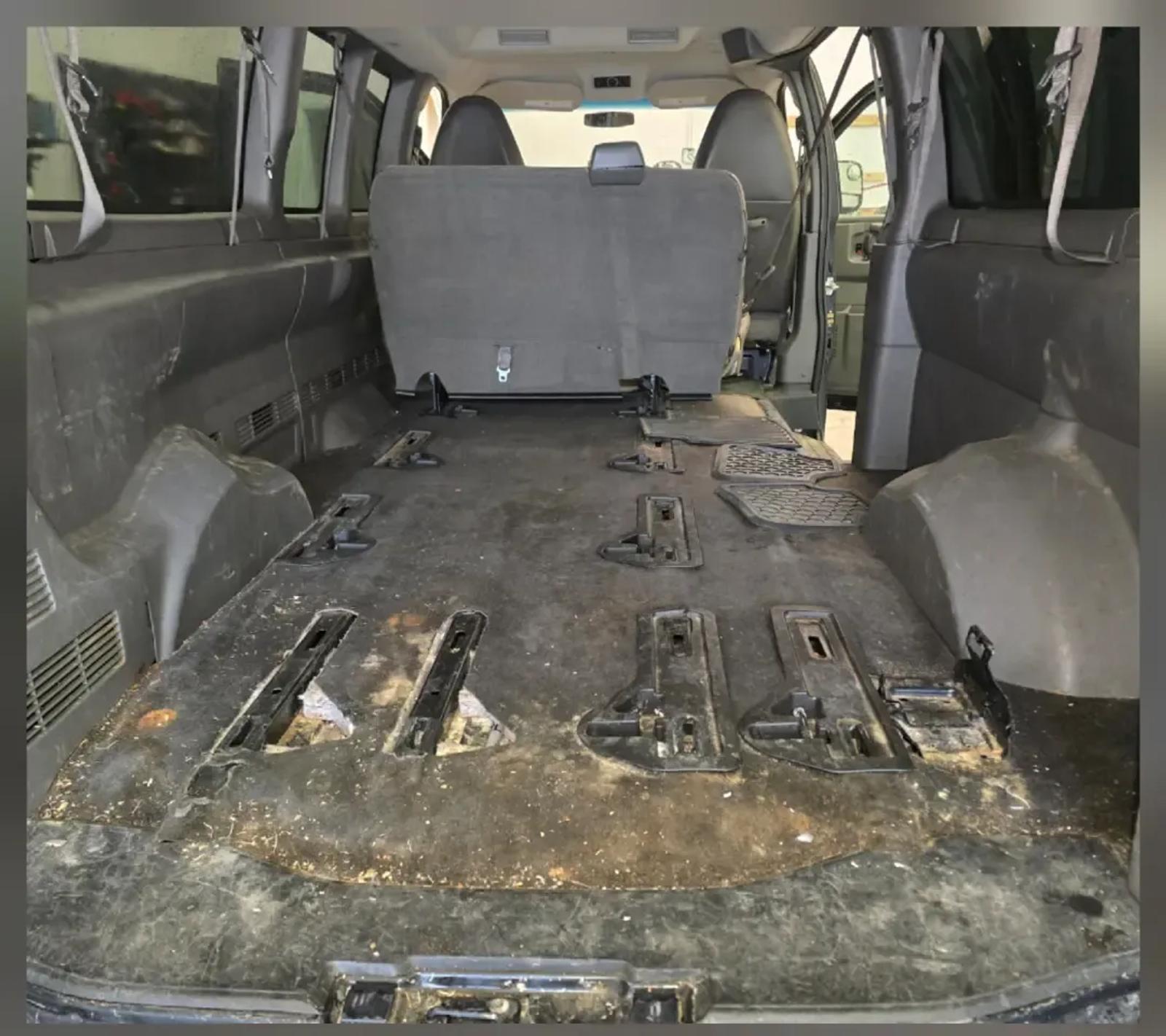 Cargo van floor covered in caked debris before carpet extraction in Anchorage, Alaska