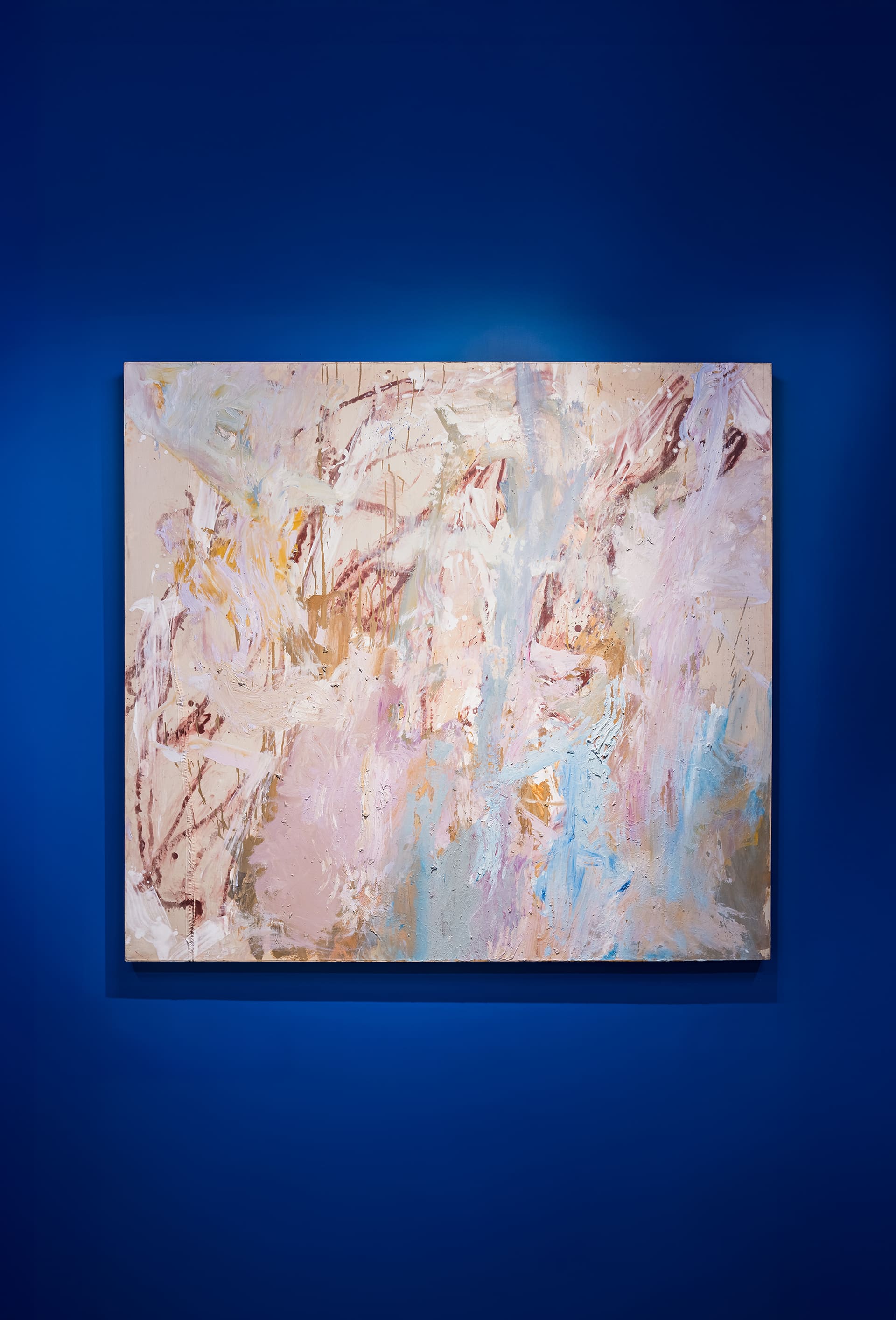 “Large abstract painting with layered, textured brushstrokes in soft pinks, blush tones, beige, cream, light blue, and hints of gold and lavender. The composition is loose and gestural, with sweeping marks and blended color areas creating a diffuse, atmospheric effect across the canvas.