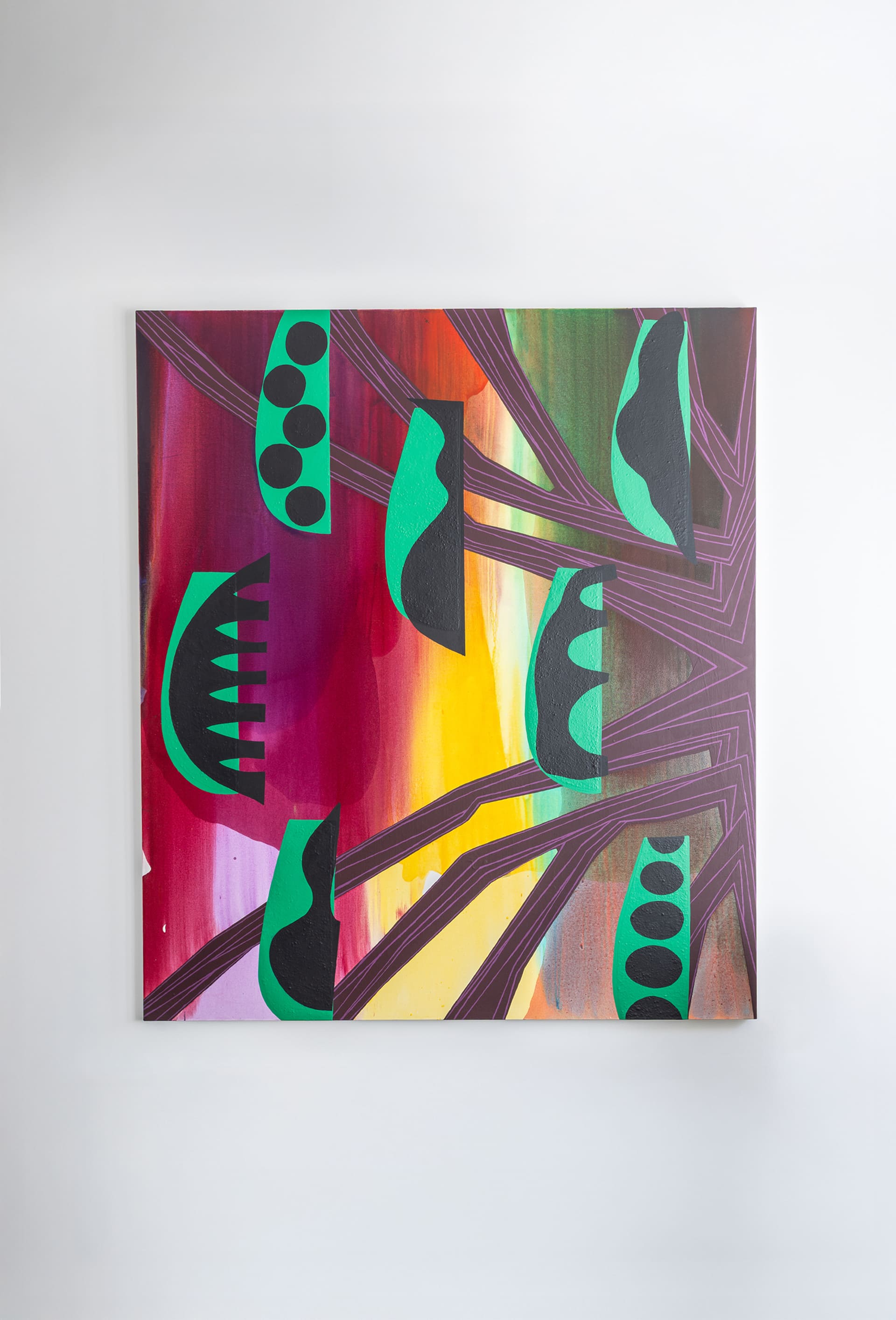 A vibrant abstract painting featuring bold geometric and organic shapes in black and green over a multicolored background of red, orange, yellow, and purple hues. The artwork is displayed on a white wall above a terrazzo baseboard.