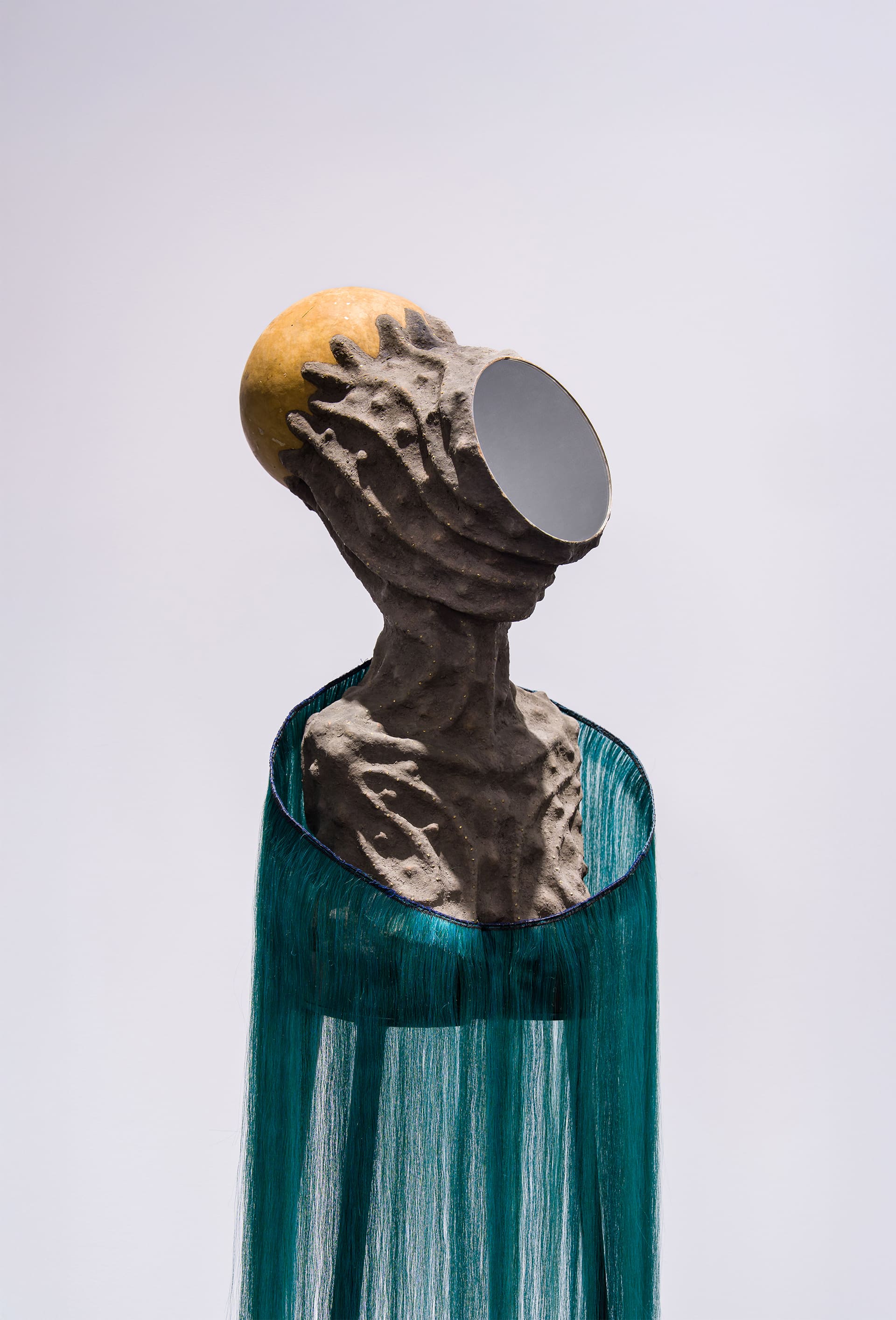 Mirror Faced I” by Wangechi Mutu depicts a sculptural figure with a female form whose face is entirely mirrored, reflecting the surrounding environment and the viewer. The figure’s body blends organic shapes with surreal, futuristic textures—smooth, sinuous surfaces contrast with fragmented, collage-like elements. The mirrored face creates a sense of anonymity and introspection, while the hybrid materials suggest themes of transformation, identity, and the intersection of human and otherworldly forms.