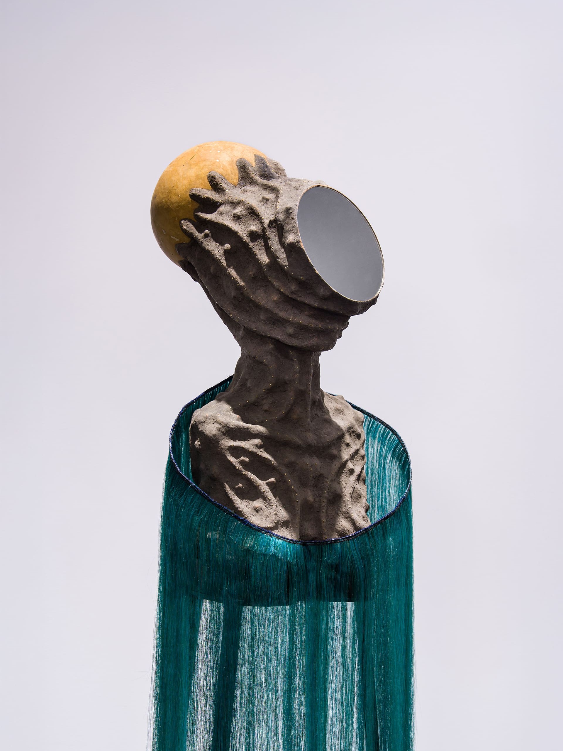 Mirror Faced I” by Wangechi Mutu depicts a sculptural figure with a female form whose face is entirely mirrored, reflecting the surrounding environment and the viewer. The figure’s body blends organic shapes with surreal, futuristic textures—smooth, sinuous surfaces contrast with fragmented, collage-like elements. The mirrored face creates a sense of anonymity and introspection, while the hybrid materials suggest themes of transformation, identity, and the intersection of human and otherworldly forms.