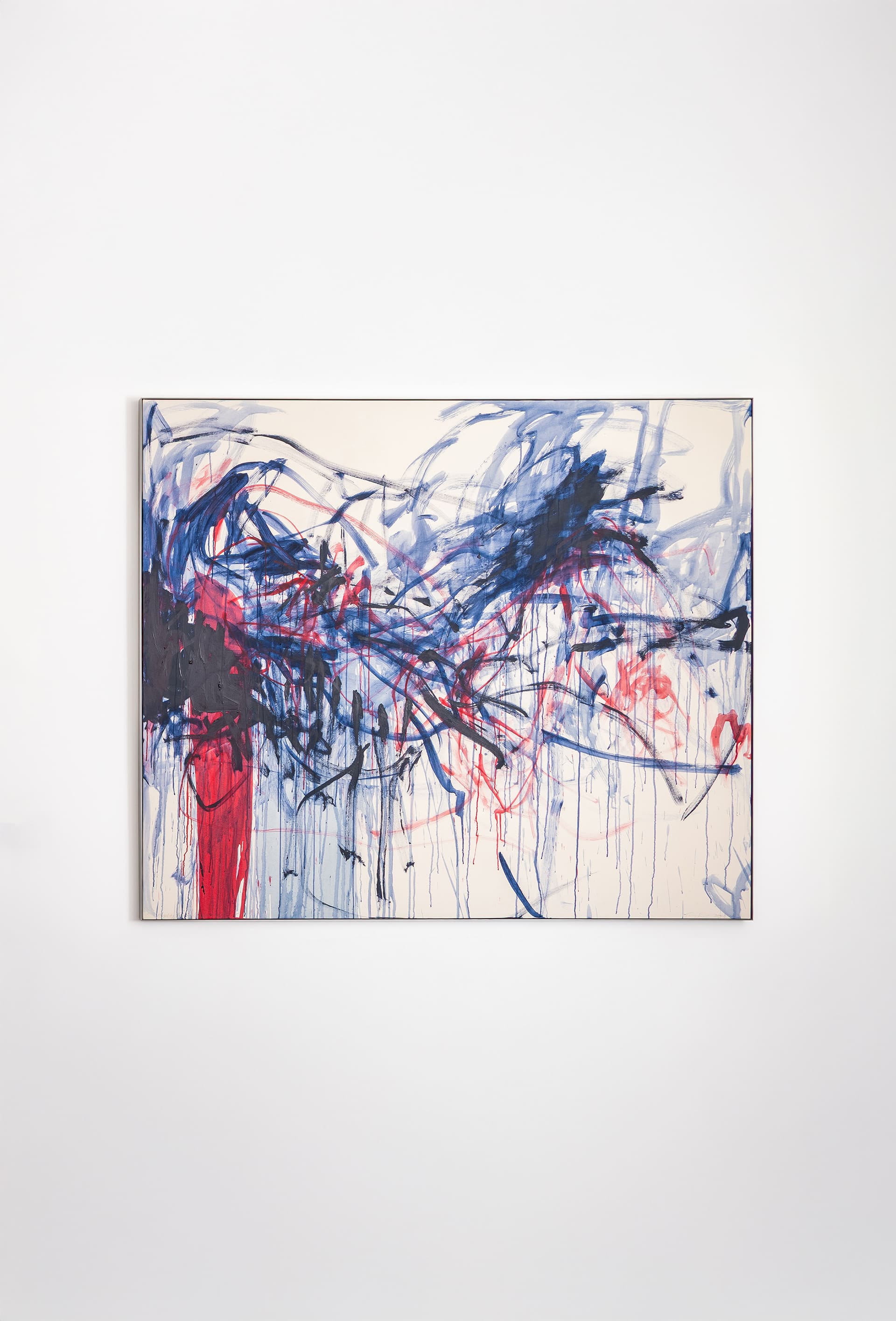 Abstract painting featuring expressive brushstrokes in deep blue, navy, black, bright red, magenta, and pale pink on a light cream background. Broad sweeping lines, drips, and layered marks overlap to form a chaotic, dynamic composition, with darker tones concentrated on the left and more dispersed strokes extending toward the right.”