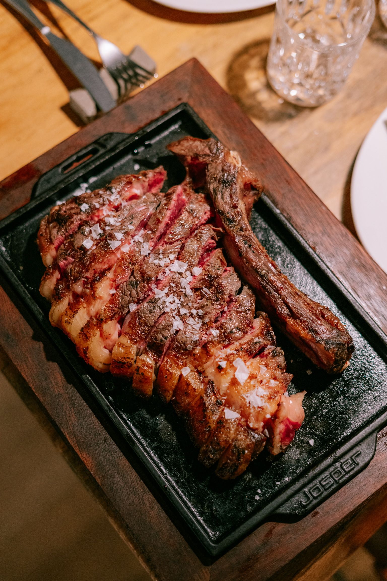 Chuletón a la brasa cortado en tiras con escamas de sal, en una plancha de hierro