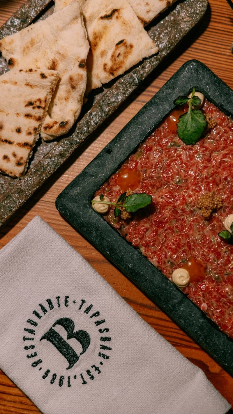 Steak tartar en una fuente de piedra con pan de pita tostado y servilleta de La Bodeguilla