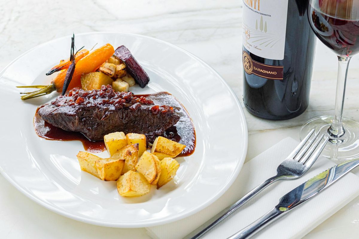 Elegant gourmet meat dish served with vegetables and a glass of red wine.