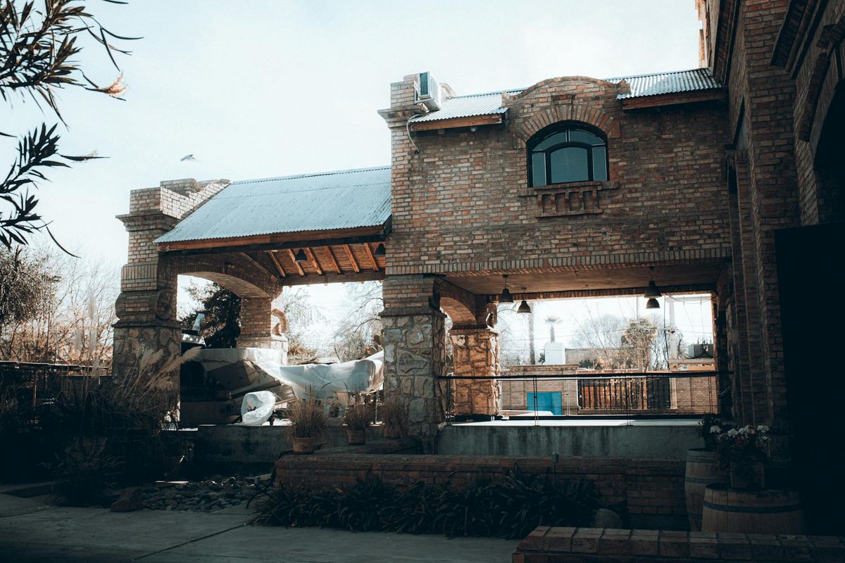 A rustic brick winery building under a clear sky, showcasing Mendoza's architectural charm.