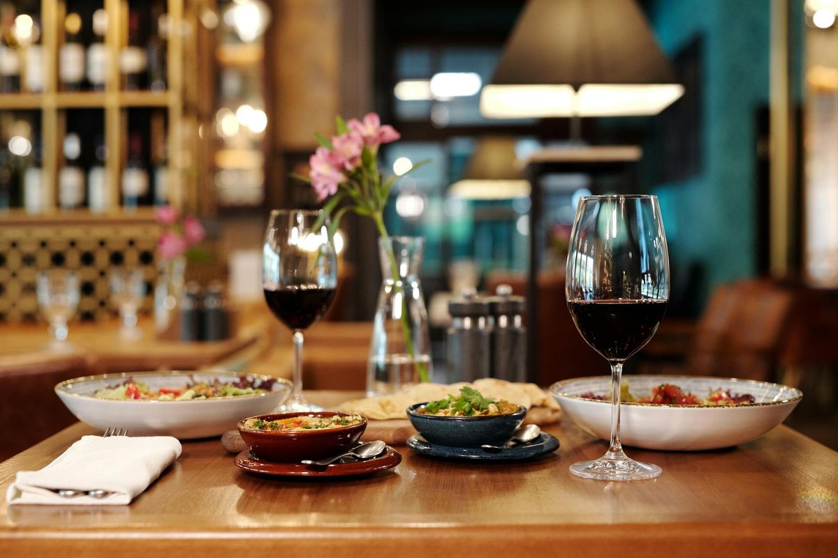 A meticulously arranged restaurant table setting with red wine and various appetizers.