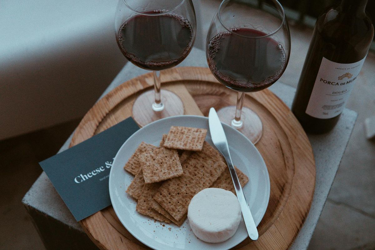A refined setup of red wine and cheese on a rustic platter, perfect for a Lisbon-themed dining ambiance.