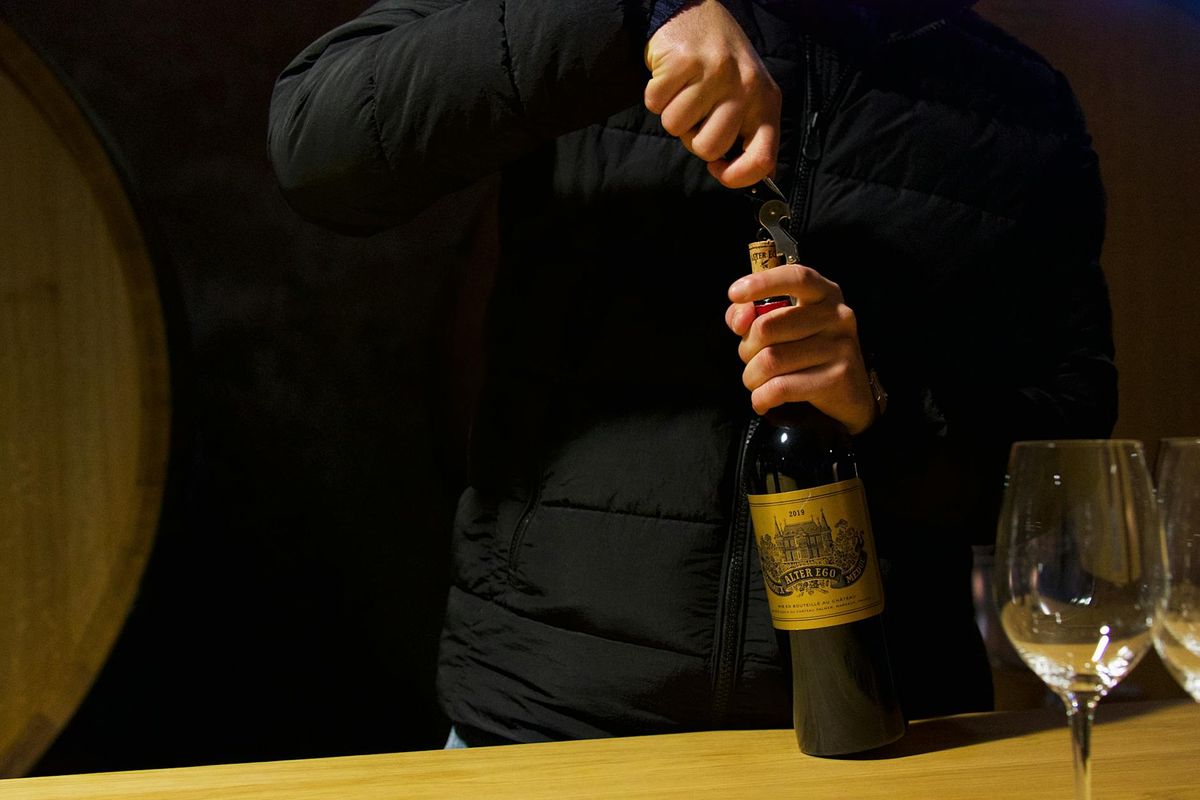 Person uncorking wine bottle in Margaux, Bordeaux. Elegant wine tasting in a French cellar.